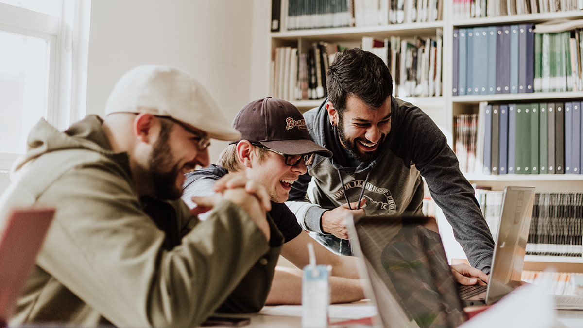 Three People Laughing in Front of a Computer: A Tale of Team Stock Photos